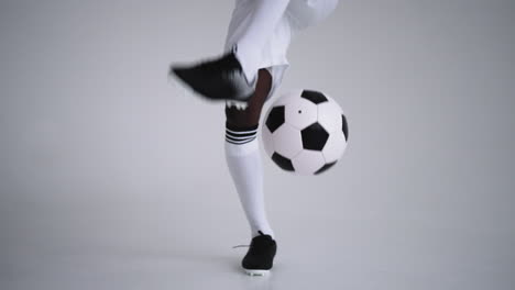Un-Jugador-De-Fútbol-Negro-Profesional-Con-Uniforme-Blanco-Sobre-Fondo-Blanco-Hace-Malabarismos-Con-Una-Pelota-En-Cámara-Lenta.-Jugador-De-Fútbol-De-Grupo-étnico-Afroamericano-Con-Un-Balón-De-Fútbol